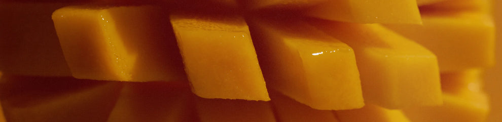 Close-up of a fresh mango sliced into a grid pattern, revealing juicy yellow-orange fruit cubes.