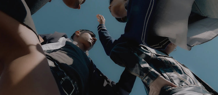 Low angle shot of a group of people in casual clothing looking down against a clear blue sky
